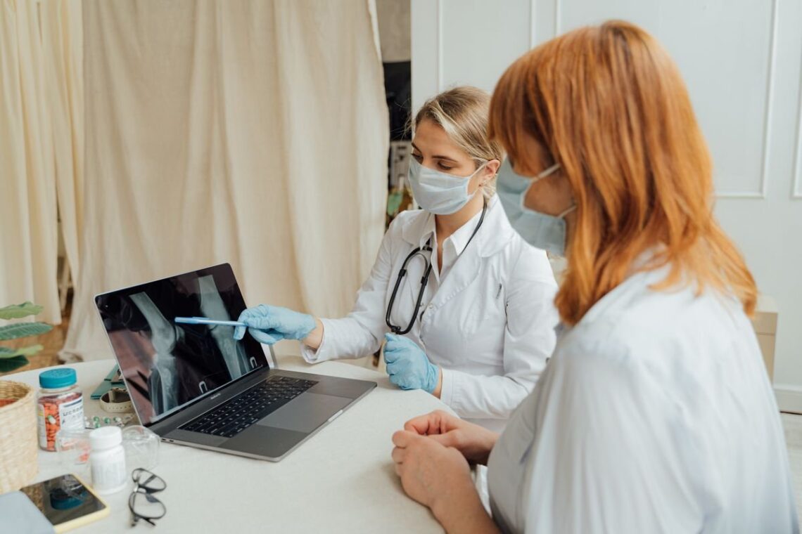 Two clinicians reviewing an X-ray image on a laptop in a clinic
