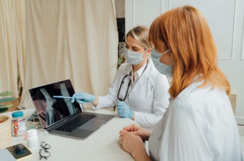 Two clinicians reviewing an X-ray image on a laptop in a clinic