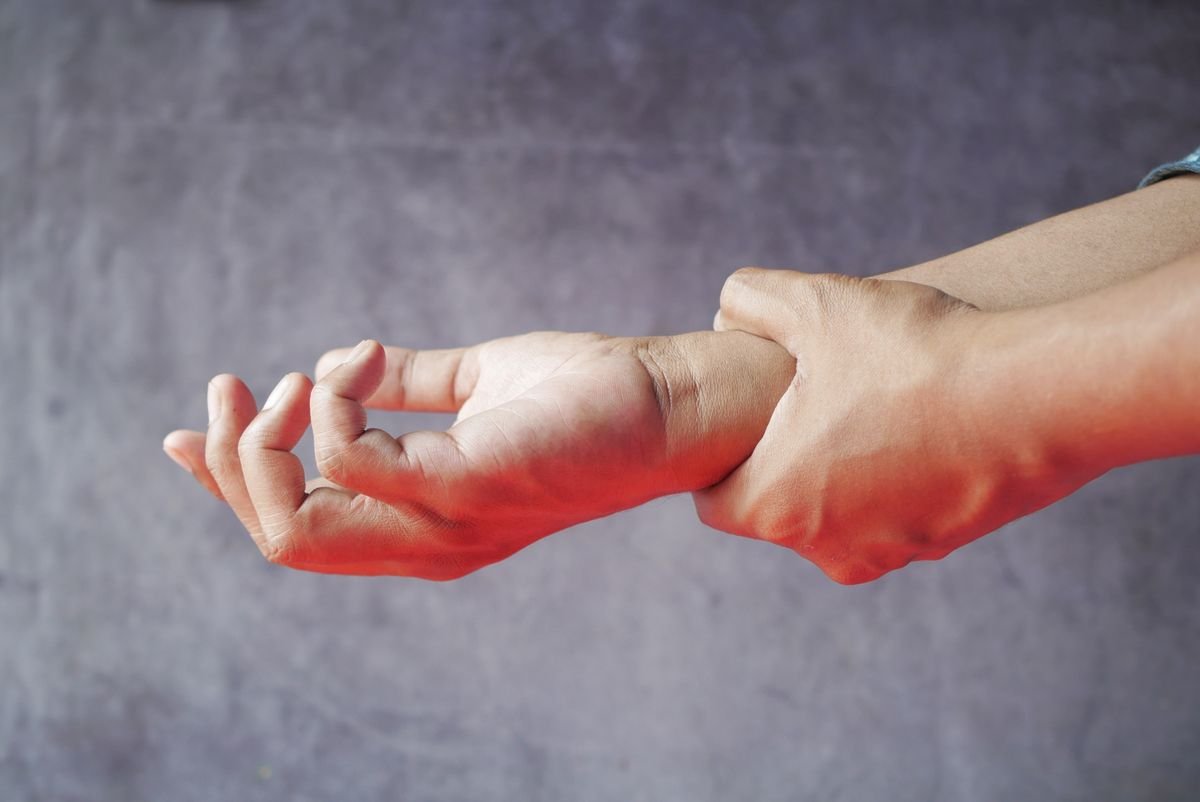 A person holding one wrist with the other hand as if it feels sore