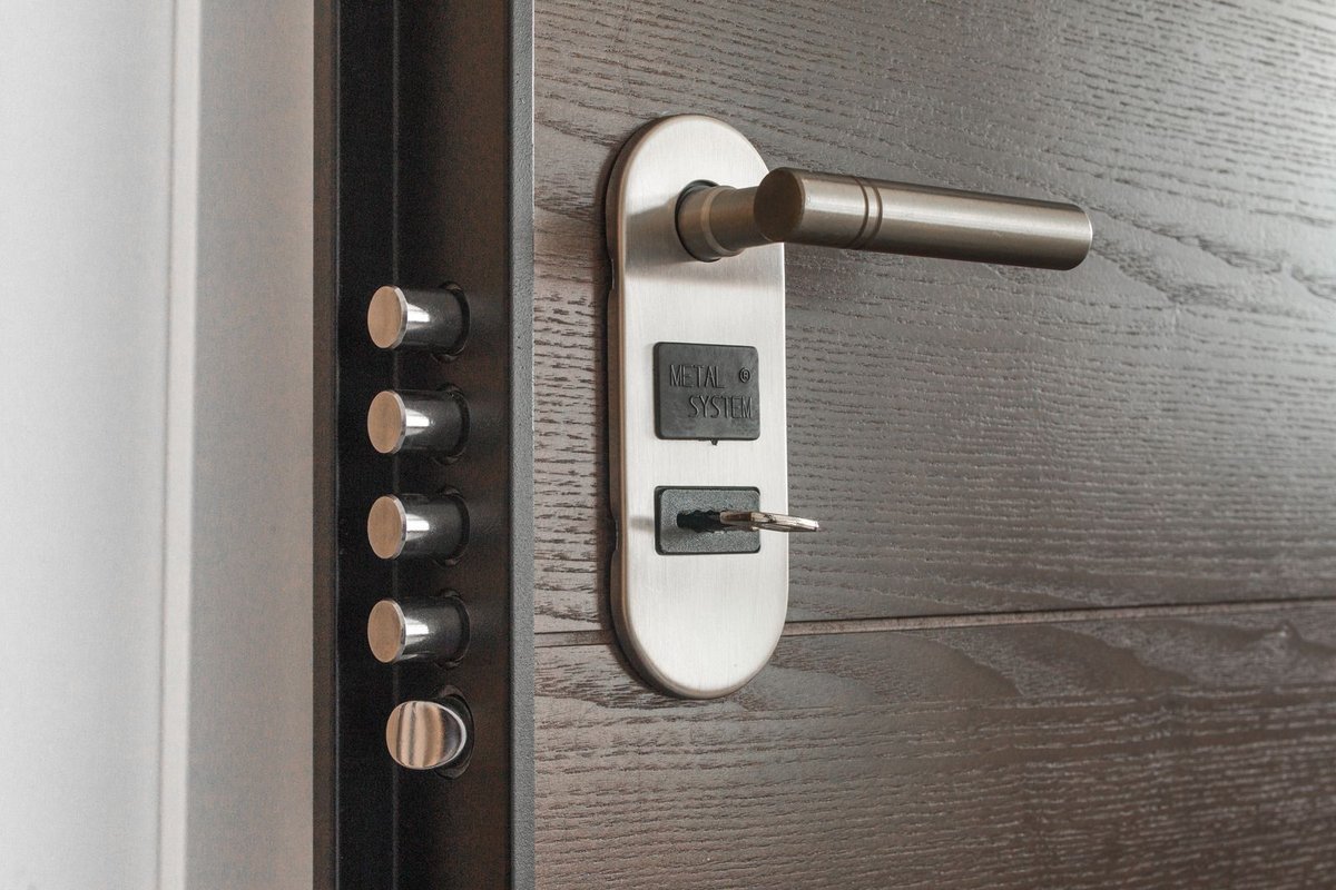 Dark wood security door with multi-bolt lock and key inserted in the cylinder